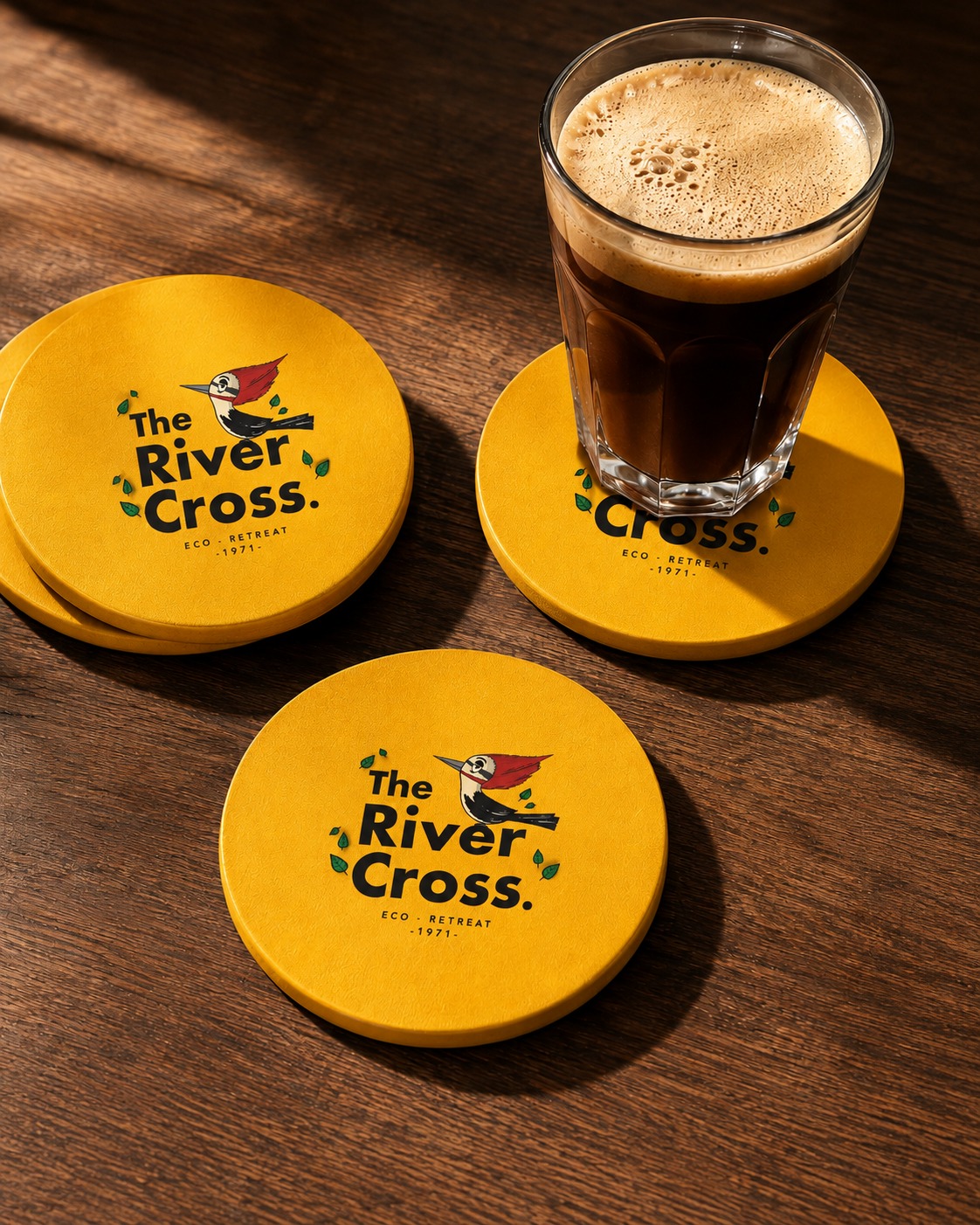 The River Cross Eco-Retreat branded coasters on a wooden table